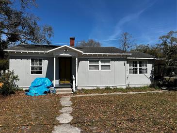 Charming single-story home with a gray exterior, a chimney, and a tidy front yard at 5493 Okaloosa Ave, Intercession City, FL 33848