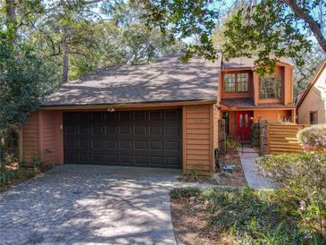 Two-story home with brown siding, brown shingled roof, a brown garage door, and a pop of color with a red front door at 136 Raintree Dr, Longwood, FL 32779