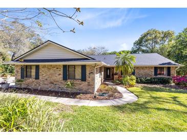 Charming single-story brick home with lush landscaping, mature trees and a welcoming walkway leading to the front door at 1575 Belfast Ct, Apopka, FL 32712