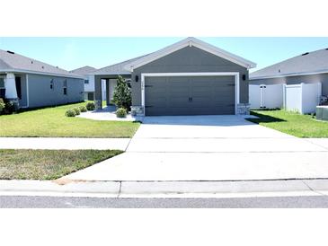 Charming single-story home with a well-manicured lawn, concrete driveway, and neutral gray exterior at 2294 Sunset Way, Davenport, FL 33837