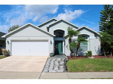 Charming home featuring a well-manicured lawn, palm trees, and a stone pathway to the front door at 2511 Crown Ridge Cir, Kissimmee, FL 34744