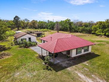 Spacious single-story home with a red roof and an attached carport, complemented by a well-maintained lawn and separate outbuilding at 2730 W Highland St, Lakeland, FL 33815