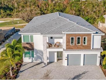 Stunning two-story home with a modern design, a balcony, three-car garage, and manicured landscaping at 480 Muirfield Loop, Reunion, FL 34747