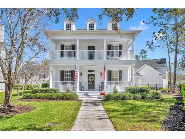 Charming two-story home featuring a spacious double porch, complemented by well-manicured landscaping and a welcoming walkway at 807 Oak Shadows Rd, Celebration, FL 34747