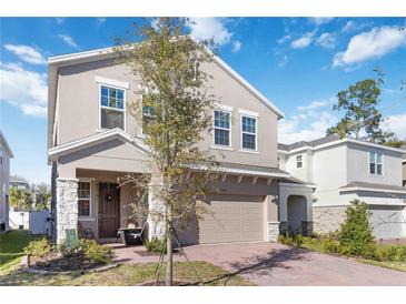 Charming two-story home boasts a neutral stucco facade, complemented by stone accents and a brick driveway at 1129 Blue Garden Dr, Deland, FL 32720