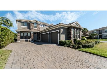 Charming two-story home featuring stone accents, three-car garage and brick paver driveway at 12189 Beach Fern Rd, Orlando, FL 32824