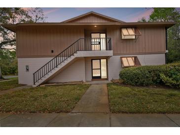 Inviting two-story exterior featuring well-maintained siding, trimmed bushes, and a staircase leading to the upper level entrance at 170 Palmetto Woods Ct # 3A, Deltona, FL 32725