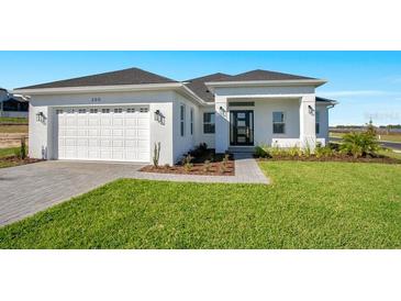 Beautiful single-story home with a white exterior, well-kept lawn, and a two-car garage at 200 Snowy Orchid Way, Lake Alfred, FL 33850