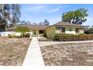 Charming yellow home with stone accents, well-manicured landscaping, and welcoming walkway at 2101 Lake Francis Dr, Apopka, FL 32712