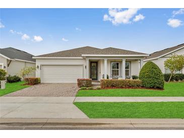 Charming single-story home with a well-manicured lawn, brick driveway, and attached two-car garage at 2949 Marlberry Ln, Clermont, FL 34714
