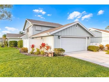 Charming home featuring a two-car garage, lush lawn, and tastefully landscaped with colorful plantings at 53 Fore Dr, New Smyrna Beach, FL 32168