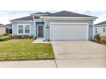 Charming single-story home featuring a light blue exterior, well-maintained lawn, and a two-car garage at 7412 Sw 76Th Ter, Ocala, FL 34481
