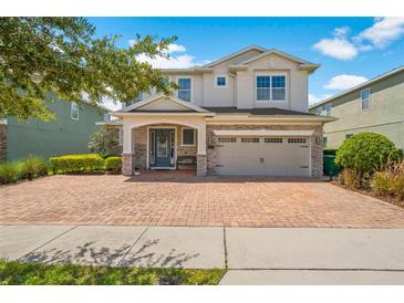 Charming two-story home with a brick driveway, manicured landscaping, and a two-car garage at 7702 Fairfax Dr, Kissimmee, FL 34747