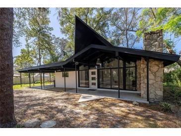 Striking mid-century modern home showcasing a unique roofline, stone chimney, and expansive windows at 812 2Nd St, Altamonte Springs, FL 32701
