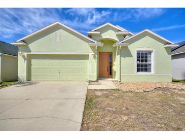 Inviting one-story home with a two-car garage, manicured lawn, and a light green exterior at 326 Cotswold Cir, Davenport, FL 33837