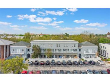 Three-story condo building with central parking, lush landscaping, and partial cloudy sky at 660 Celebration Ave # 220, Celebration, FL 34747