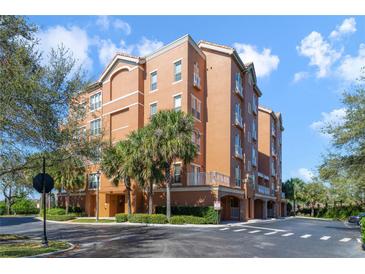 Low angle exterior shot of a condo building with orange stucco and palm trees at 7508 Toscana Blvd # 123, Orlando, FL 32819