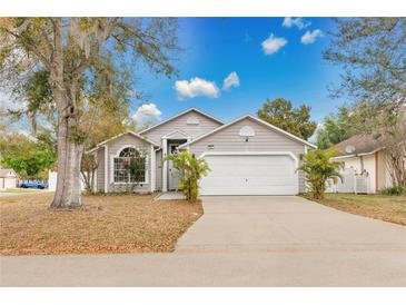 Charming single Gathering home featuring a two-car garage and nicely landscaped front yard under a sunny blue sky at 102 Ethan Ave, Davenport, FL 33897