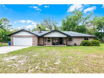 Charming brick home with an attached garage and inviting front porch under a sunny, blue sky at 1095 Grand Ave, Orange City, FL 32763