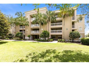 Multi-story building with balconies, set among palm trees, and a lush green lawn on a bright, sunny day at 1360 Centre Court Ridge Dr # 201, Reunion, FL 34747