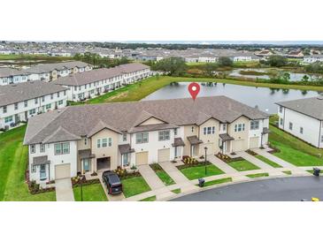 Aerial view of townhomes by a pond, showcasing location and nearby community at 730 Longboat Dr, Davenport, FL 33896