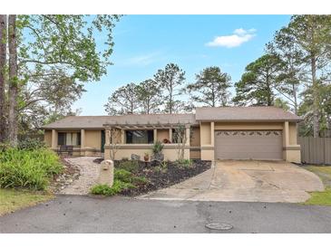 Ranch-style home featuring a well-maintained yard, two car garage, and a charming front walkway with a pergola at 811 Gatehouse Dr, Winter Springs, FL 32708
