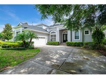 Charming single-Gathering home featuring a well-manicured lawn, mature trees, and an attached two-car garage at 11537 Claymont Cir, Windermere, FL 34786