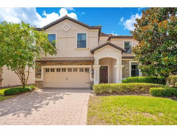 Charming two-story home featuring a brick driveway, two-car garage, and lush landscaping at 1445 Rolling Fairway Dr, Davenport, FL 33896