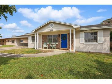 Charming single-story home featuring a brick facade, covered porch, and a bright blue front door at 1612 Eastbrook Blvd, Winter Park, FL 32792