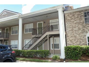 Exterior view of a two-story condo building with staircase access and neatly trimmed landscaping at 164 Reserve Cir # 208, Oviedo, FL 32765