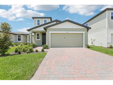 Charming home featuring a two-car garage, brick driveway, and beautifully landscaped front yard at 3213 Viceroy Ct, Poinciana, FL 34759
