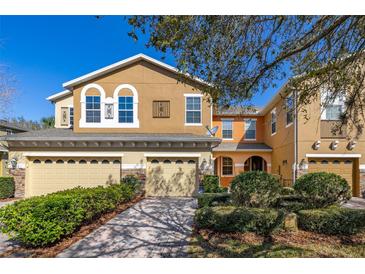 Charming two-story townhome featuring a two-car garage, beautifully landscaped yard, and colorful exterior at 5252 Hidden Cypress Ln, Oviedo, FL 32765