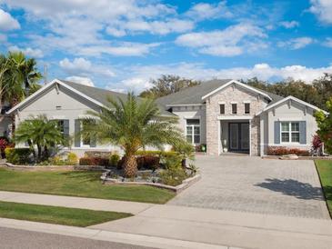 Charming single-story home featuring a brick-paved driveway, well-manicured lawn, and beautiful landscaping at 8400 Bridgeport Bay Cir, Mount Dora, FL 32757
