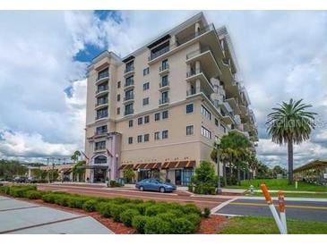 Beautiful condo building with awnings, palm trees, manicured lawn, and blue skies at 111 E Monument Ave # 705, Kissimmee, FL 34741