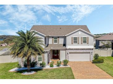 Beautiful two-story home featuring a brick driveway, stone accents, and a lush, green front yard with a palm tree at 1880 Bonser Rd, Minneola, FL 34715