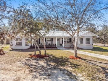 Charming single-story home featuring a metal roof and a welcoming front porch with a hammock and rocking chairs at 2466 R E Byrd Rd, Frostproof, FL 33843