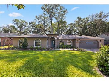 Charming single-story home features arched windows, a well-manicured lawn, and lush landscaping at 35624 Cypress Ct, Leesburg, FL 34788