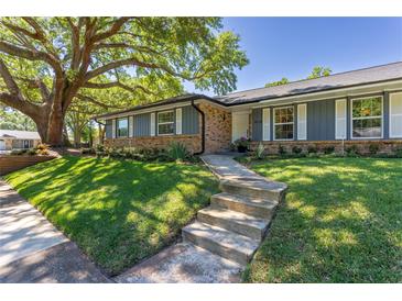 Charming single-story home with blue painted siding and brick accents, and mature tree in a well-landscaped front yard at 7614 Lake Dr, Belle Isle, FL 32809