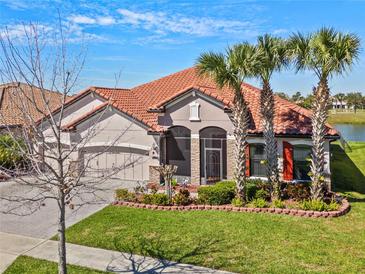 Home featuring a three-car garage, tile roof, stone accents, and front lawn at 2541 Shoal Bass Way, Kissimmee, FL 34746