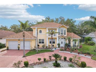 Beautiful two-story home featuring a Spanish tile roof, lush landscaping, and a circular driveway at 2747 Kissimmee Bay Cir, Kissimmee, FL 34744