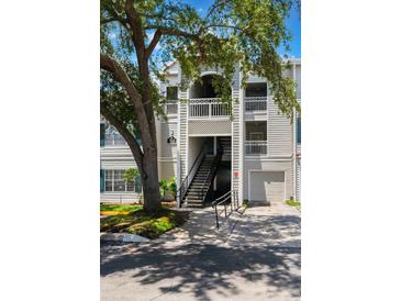 Exterior view of a condo with garages, staircases, and balconies, set against a blue sky at 5144 City St # 238, Orlando, FL 32839