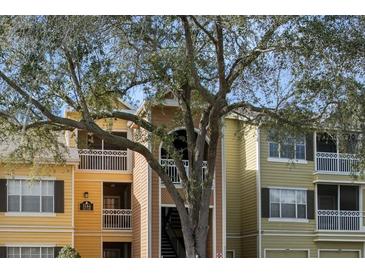 Exterior view of a multi-Gathering complex featuring balconies and a mature tree in the front at 5144 City St # 238, Orlando, FL 32839