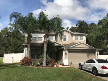 Inviting two-story home featuring a manicured lawn, mature palm trees, and an attached two-car garage at 5644 Ansley Way, Mount Dora, FL 32757