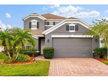 Charming two-story home with a brick driveway, mature landscaping, and a gray exterior paint at 14318 Fieldstone Lake Way, Orlando, FL 32824