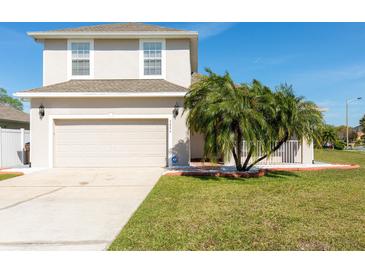 Charming two-story home featuring a well-manicured lawn, a two-car garage, and a beautiful palm tree at 3006 Mandolin Dr, Kissimmee, FL 34744
