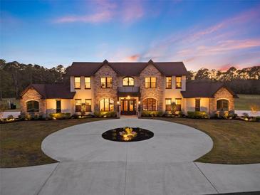 Elegant two-story home featuring a circular driveway, stone accents, and lush landscaping at twilight at 5500 State Road 33, Clermont, FL 34714