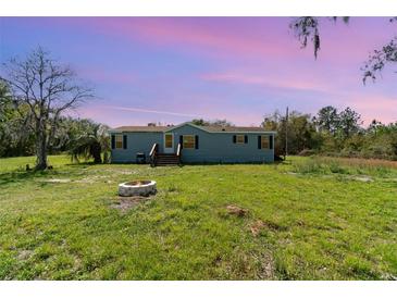 Charming blue single-Gathering home with a well-maintained lawn and a welcoming fire pit at 7322 Groveland Farms Rd, Groveland, FL 34736