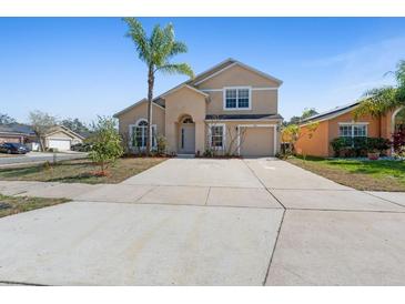Two-story home featuring neutral stucco, an attached garage, and a well-manicured lawn with palm tree at 877 Scrub Jay Way, Davenport, FL 33896