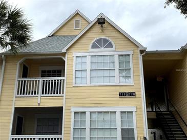 Two-story condo features light yellow siding, white trim, and a balcony on the second floor at 1081 S Hiawassee Rd # 723, Orlando, FL 32835