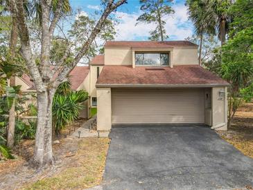 Beige two-story home featuring an attached two-car garage, asphalt driveway, and mature landscaping at 117 Starling Ln, Longwood, FL 32779
